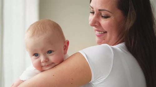Loving Mother Holding Cute Infant Indoors