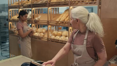 Senior Cashier Working with Help of Colleague in Bakery