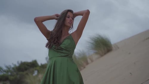Professional dark haired women posing confidant thinkful and seductive on a sand dune beach with clo