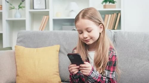 Girl Smiling and Holding Cellphone on Couch