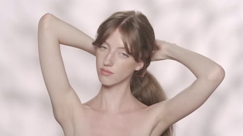Woman Ties Her Brown Hair Into a Ponytail