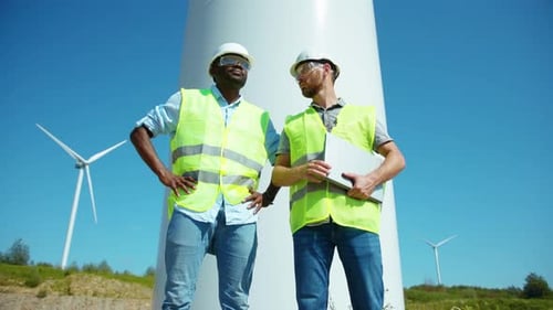 Zwei Arbeiter in Uniform diskutieren über den Windturbinenstand, ökologische Energiewirtschaft, elektrische Windmühle