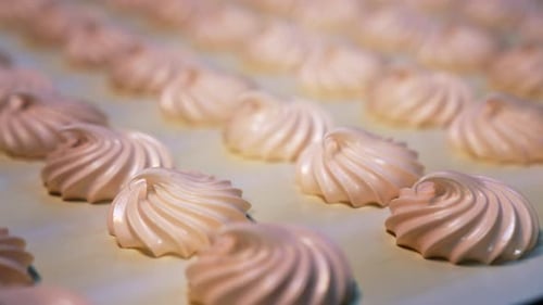 Conveyor belt with freshly-made sweet marshmallows. Close look at the creamy desserts.