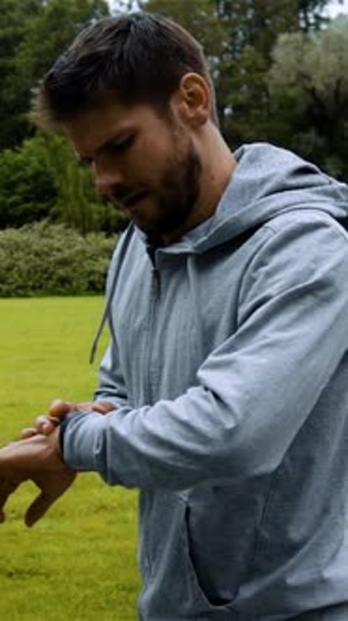Vertical of Man Running in Green Park Woods Training and Look at Smart Watches