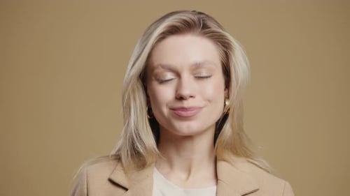 Smiling blonde woman in blazer against neutral background