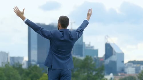 Successful Businessman Raising Arms in City Park