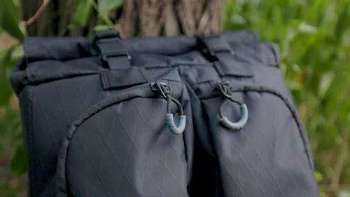 close up macro shot of black zipper pull and fabric of modern backpack with buckles