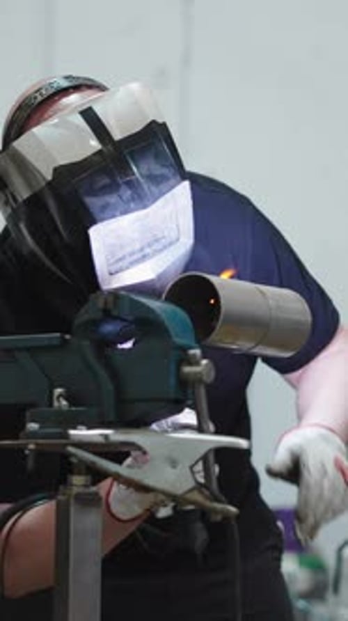 Man Welding Metal Pipe with Protective Gear