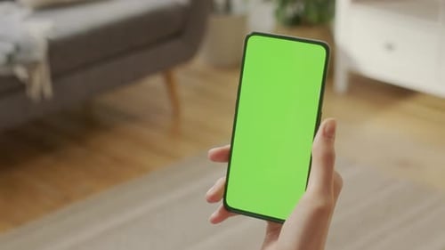 Back View of Woman Holding Chroma Key Green Screen Smartphone Watching Content Without Touching or