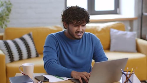 Young man working at computer at home desk