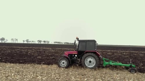 Red tractor plowing the field in Ukraine