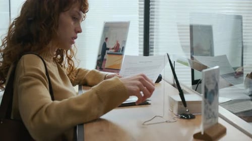 Woman Reviewing and Signing Documents in Modern Bank Office