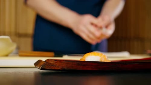 Closeup in Japanese Restaurant the Chef Lays Out Pieces of Raw Fish on a Plate