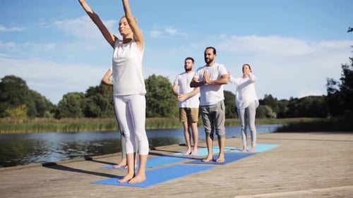 Fitness, Sport, And Healthy Lifestyle Concept - Group Of People Making Yoga Exercises On River Or...