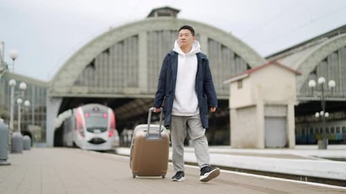 Man asian passenger arrives or departure by train home in town, with big suitcase, tourist