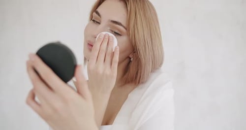 Woman Applies Makeup With Sponge and Compact Mirror