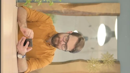 Excited Man Celebrating Success with Mobile Phone Indoors