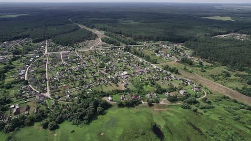 Aerial View of a Large Village with Private Backyards Surrounded By Meadows and Forests