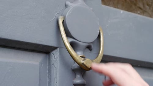 Close up of a man using a door knocker to knock on a door