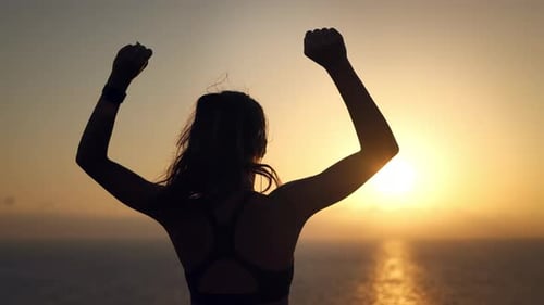 Woman Celebrating Success at Ocean Sunset