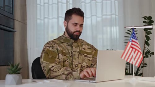 Caucasian Man in Military Uniform Typing at Laptop By Desk with USA Flag