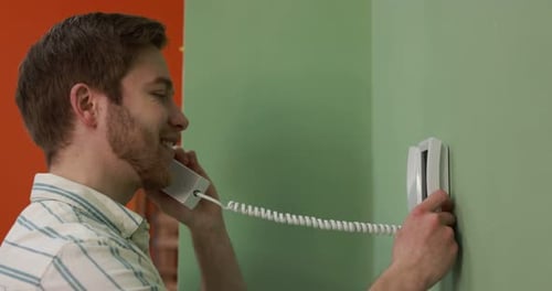 Young man answering intercom call at home