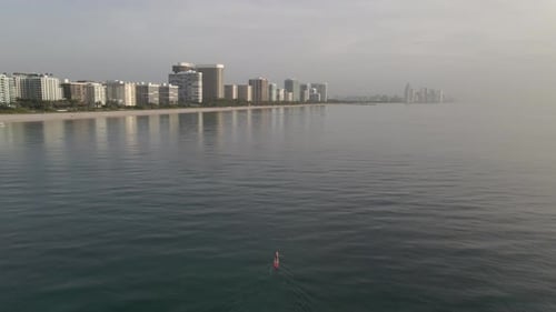 Sunrise aerial: Stand up paddleboarder on calm ocean at Surfside Beach