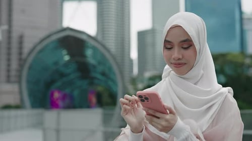 Charming Young Muslim Girl in Traditional Clothes Standing Outside and Scrolling Pictures in Social