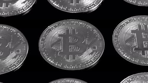 Bitcoins auf schwarzem Hintergrund drehen sich langsam in Schwarzweiß