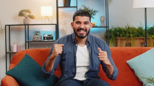 Excited Man Gesturing on Orange Couch