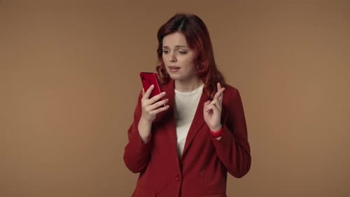 Medium Isolated Video of a Woman Holding a Smartphone in Her Hand Crossing Fingers Waiting for the