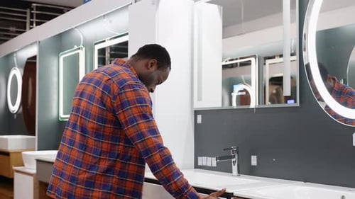 Young Man in a Furniture Store Looks at the Furniture for Bathroom