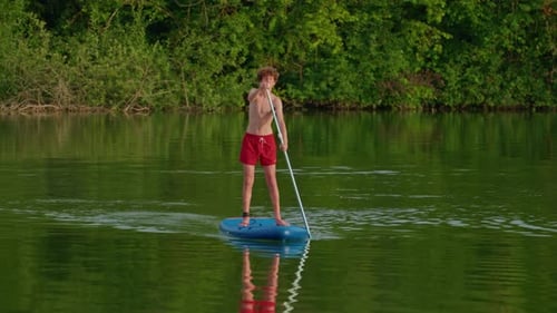 Alone Boy Floating on Stand Up Paddle Board in Lake in Summertime Standup Paddleboarding Surfer Rows