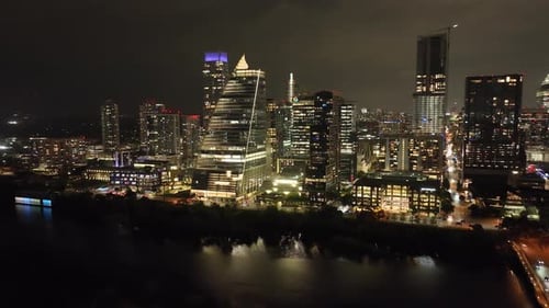 Downtown Austin, Texas skyline at night with drone video moving left to right in a circle.