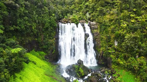 Drone slowly moving towards a waterfall at high rocky cliff. 4K videos.