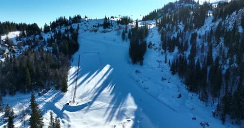A ski resort in a mountain range dotted with pine forests on a clear sunny day