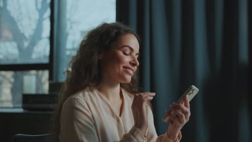 Smiling woman scrolls on her smartphone in interior