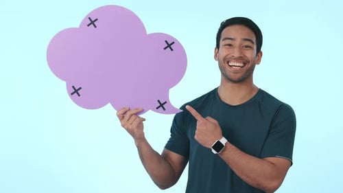Happy asian man, speech bubble and pointing to mockup in advertising against a studio background