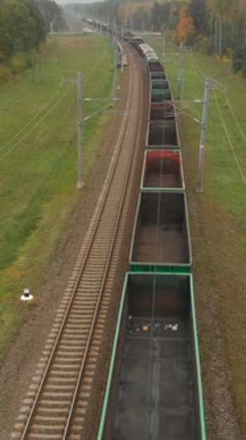 Vertical Top View of a Long Freight Train Moving Along the Railway Tracks
