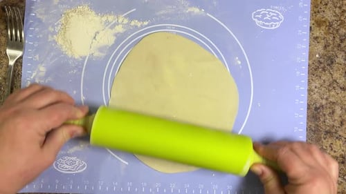 Rolling out round pieces of raw dough with a rolling pin to make patties. Top view.