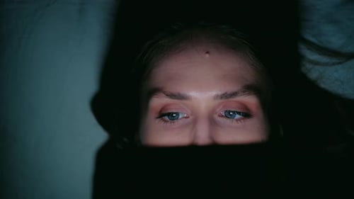 Woman Using Tablet at Night in Bed