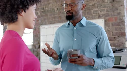 Happy diverse colleagues talking and drinking coffee in office in slow motion