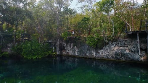 Aerial view of a beautiful Mayan cenote with turquoise water surrounded by the jungle on a nice sunn