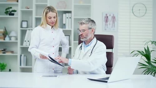 A team of doctors is holding a meeting in a modern hospital clinic. A female pediatrician shows