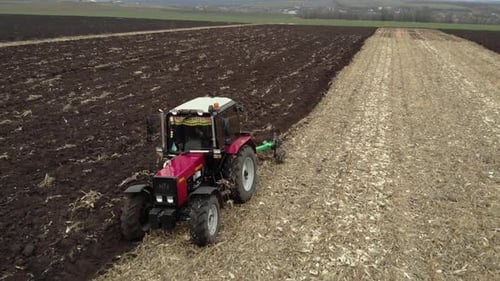 Red tractor plowing the field in Ukraine