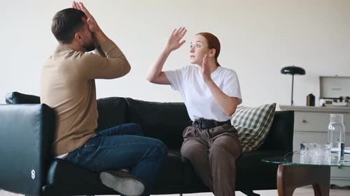 Side view of couple that are arguing. Sitting on sofa.