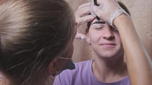 Aesthetician Colors the Eyebrows of a Young Adult