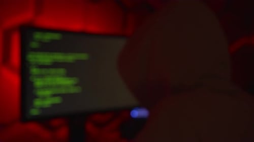 Anonymous hacker in a hoody writing code