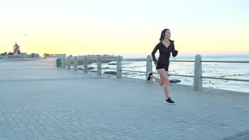 Fitness, woman and running with earphones at beach sidewalk for energy, marathon