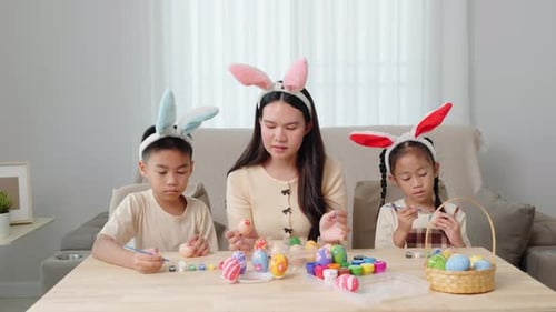 Family Decorating Easter Eggs with Bunny Ears Indoors